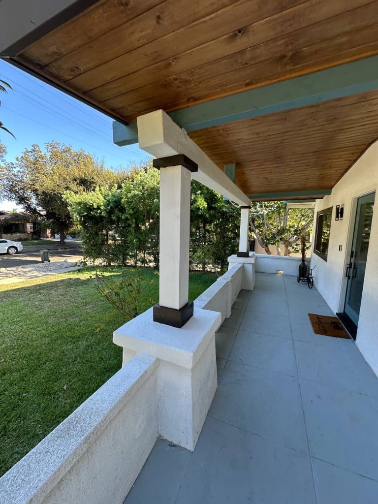 Finished porch column restoration with fresh stucco, dark trim caps, and crisp paint